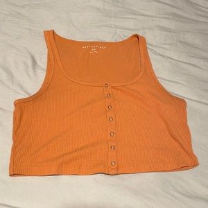 Orange cropped tank top with buttons along shirt.